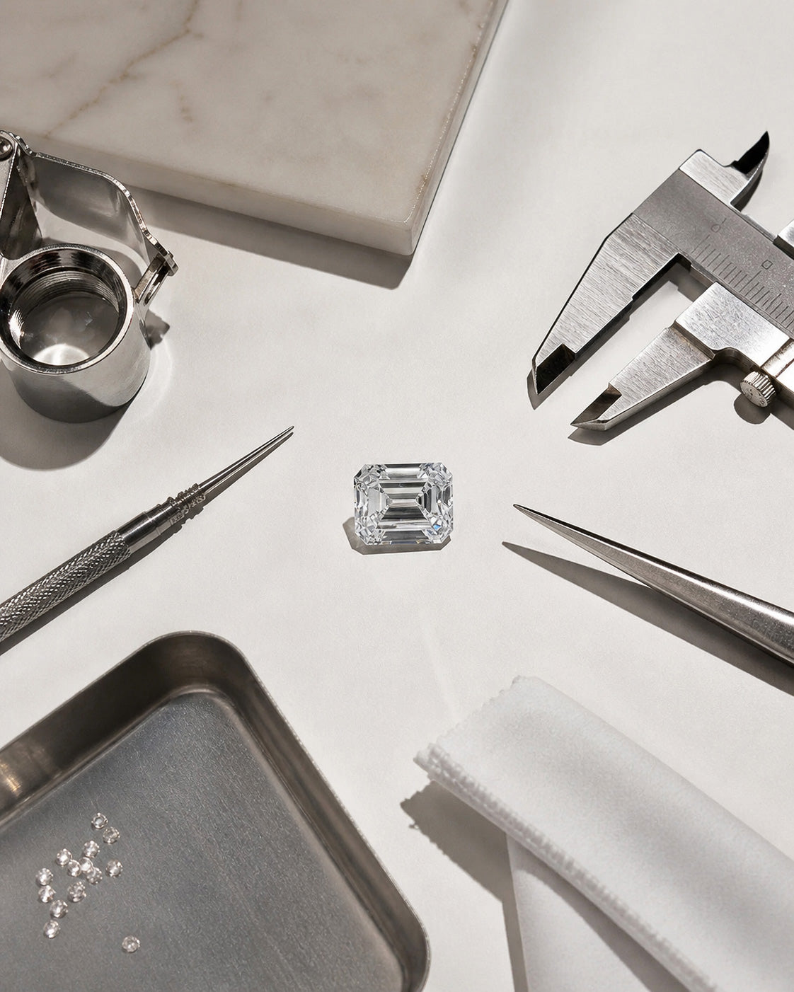 Emerald cut diamond displayed with jeweler tools and loose stones in a luxury workshop setting by William Edouard