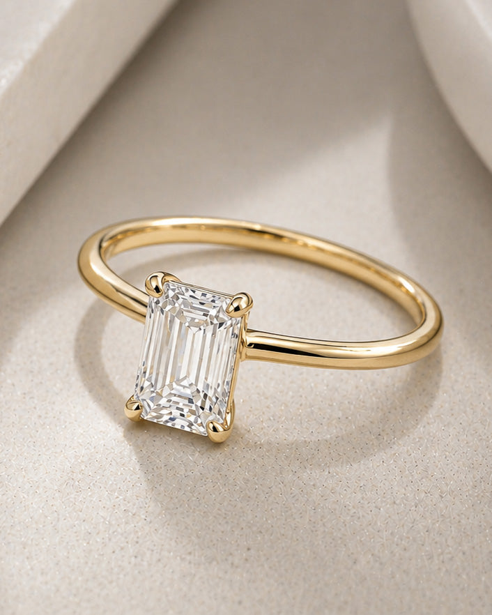 Emerald cut diamond solitaire ring in yellow gold with four prong setting by William Edouard