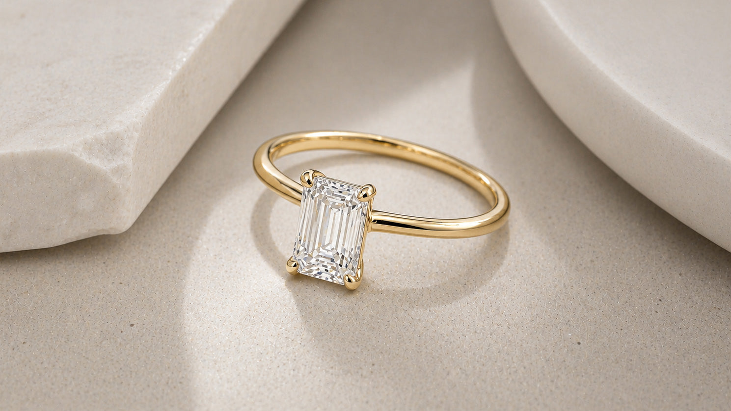 Emerald cut diamond solitaire ring in yellow gold with four prong setting by William Edouard