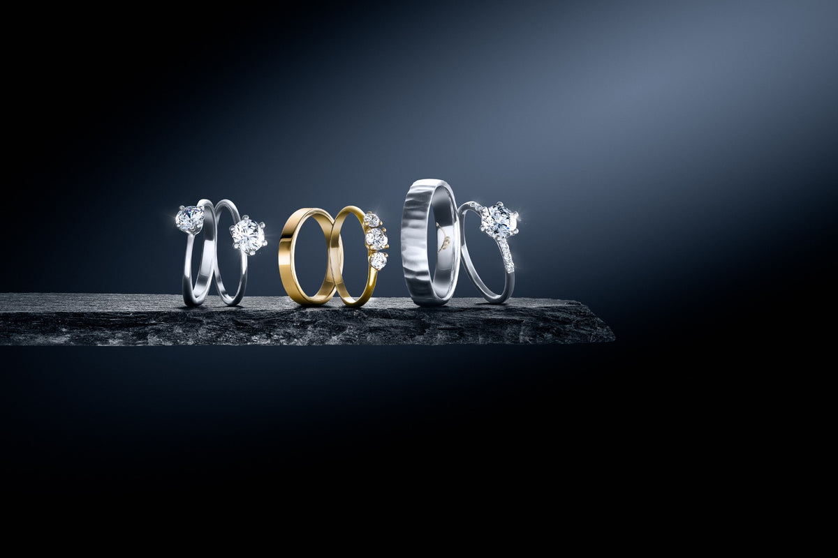 Diamond engagement rings and gold wedding bands on a slate ledge