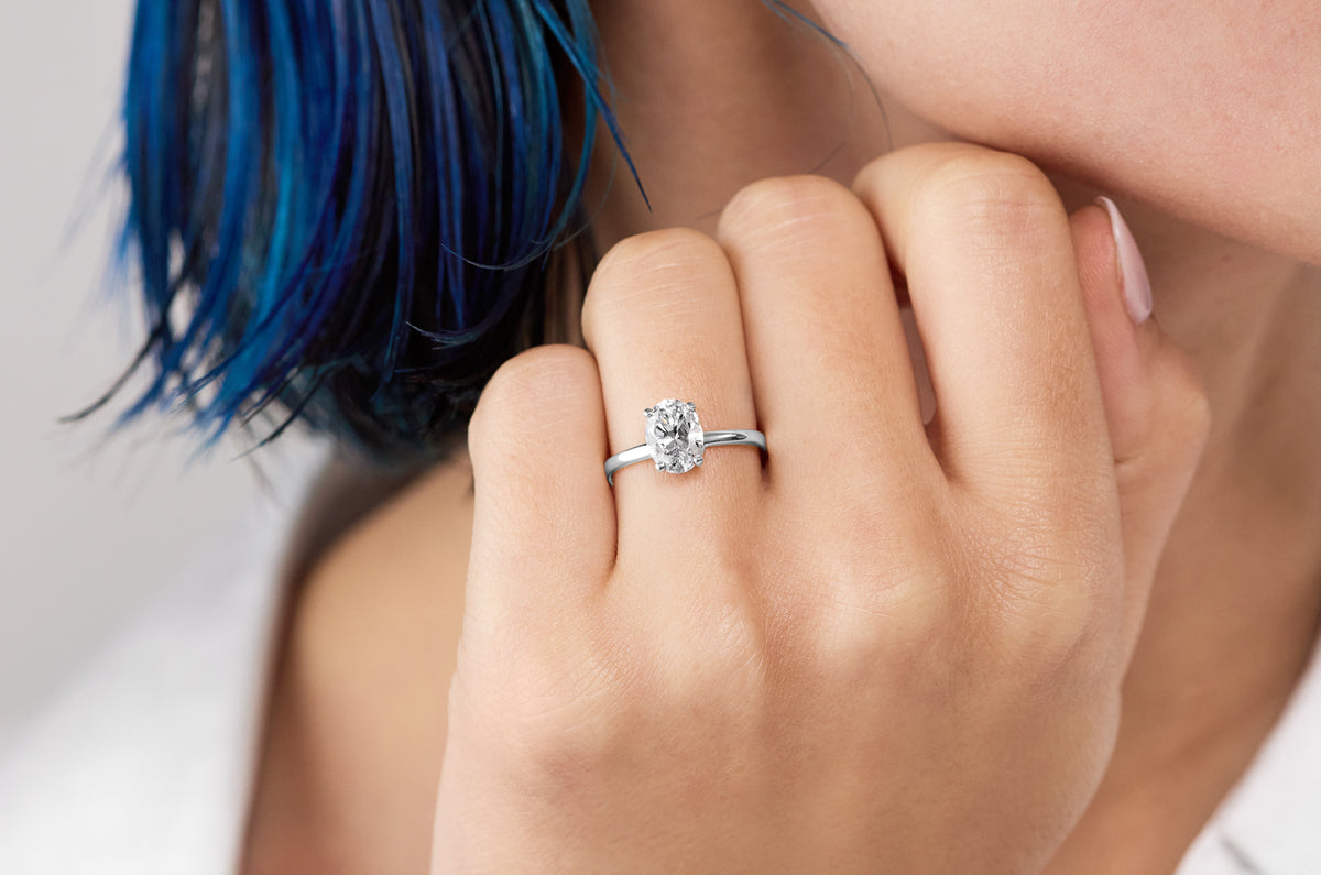Oval diamond solitaire engagement ring in white gold on hand by William Edouard