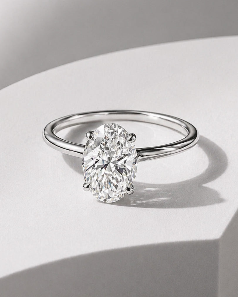 Oval diamond solitaire engagement ring in white gold with a classic four prong setting by William Edouard