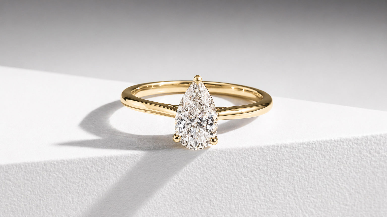 Elegant pear cut diamond solitaire engagement ring in yellow gold by William Edouard