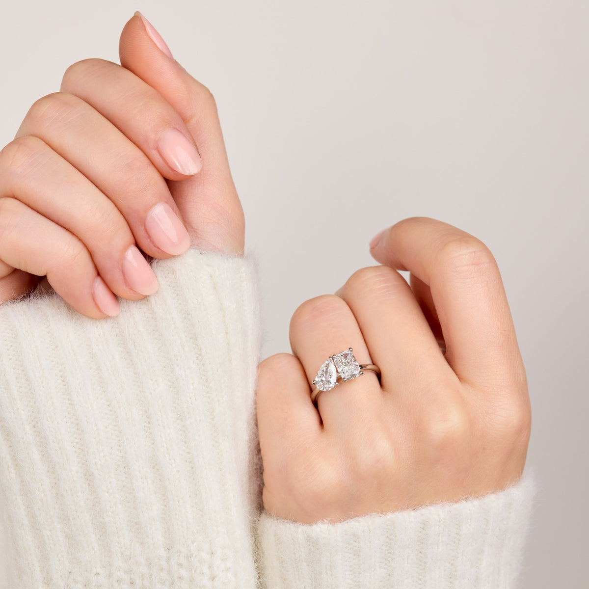 Toi et moi engagement ring with a pear and elongated cushion diamond, worn on the hand