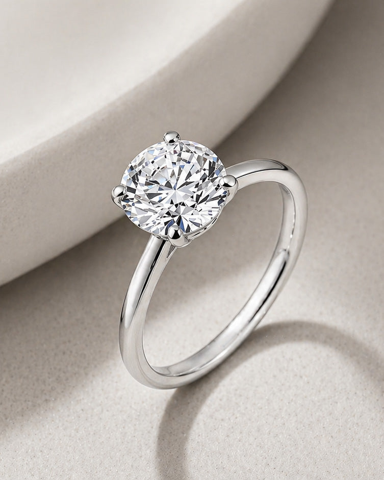 Round diamond solitaire engagement ring in white gold with four prong setting by William Edouard